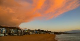 Snow clouds meet sunrise over the beach huts on Abersoch main beach